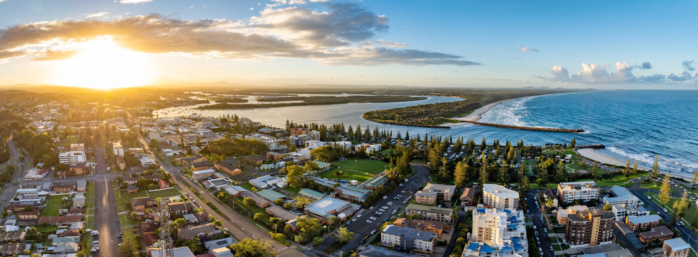 Aerial panorama of Port Macquarie at sunset, showing the coast, river mouth, and town